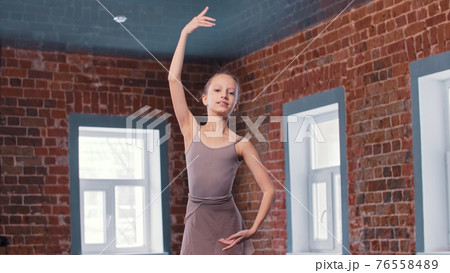 A little skinny ballerina girl training movements in the studio - looking in the camera 76558489