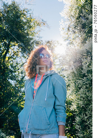 Young woman standing outdoors in green blooming park 76560277