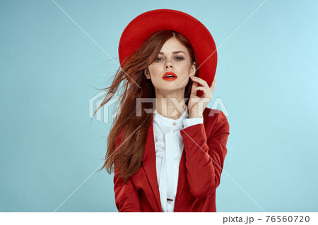 Beautiful woman in red hat jacket red lips long hair charm blue background Beautiful woman in red hat jacket red lips long hair charm blue background 76560720