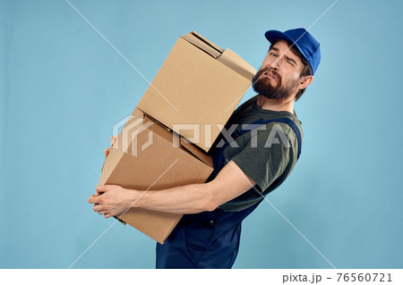 Man in working uniform with boxes in hands delivery service blue background 76560721