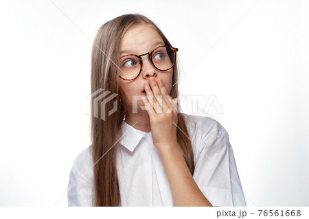 Girl in white shirt and glasses gestures with hand emotions light background studio Girl in white shirt and glasses gestures with hand emotions light background studio 76561668