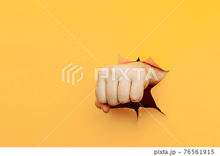 Fist punching through yellow paper background. Threat, fight and combat sports Fist punching through yellow paper background. Threat, fight and combat sports 76561915