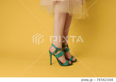 Female feet green shoes elegant style fashionable shoes yellow background Female feet green shoes elegant style fashionable shoes yellow background 76562308