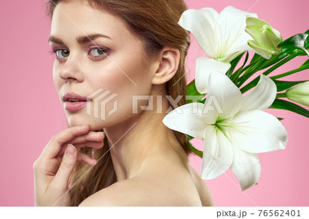 Portrait of woman with white flowers beautiful face pink background naked shoulders 76562401