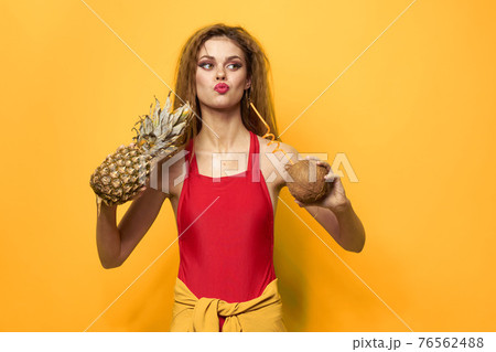 woman with pineapple and coconut cocktail exotic fruits summer lifestyle yellow background 76562488