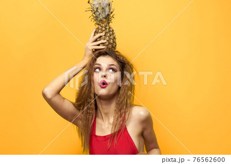 woman with pineapple in hands white t-shirt Exotic summer fun yellow background woman with pineapple in hands white t-shirt Exotic summer fun yellow background 76562600