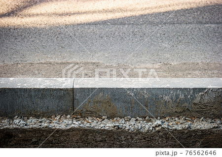 Asphalt Surface Separated By Concrete Border. Road And Sidewalk Divided By Newly Installed Concrete Curb Asphalt Surface Separated By Concrete Border. Road And Sidewalk Divided By Newly Installed Concrete Curb 76562646