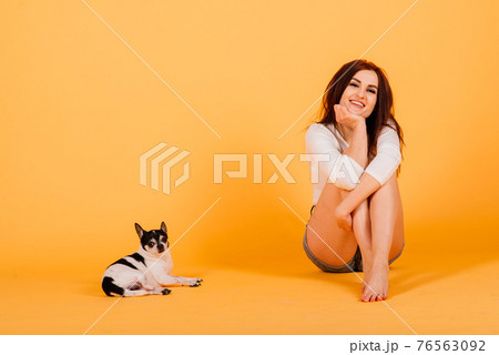 Woman and dog. Man and animal. Brunette holding chihuahua in the studio on a grey background. Woman and dog. Man and animal. Brunette holding chihuahua in the studio on a grey background. 76563092