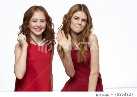 Cheerful mom and daughter next to red dresses hugs lifestyle light background smile 76563327
