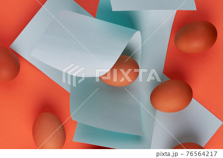 Chicken eggs and blue paper pieces. 76564217