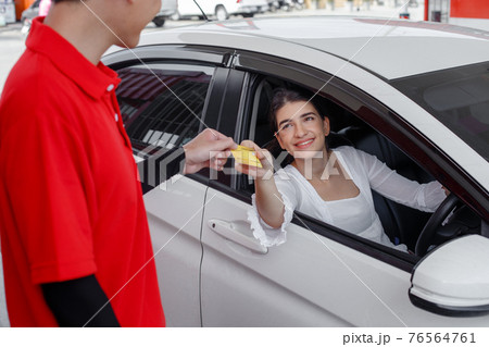 woman in car paying credit card after refuel car with man service employee gas station. 76564761