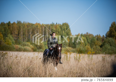 Cute girl equestrian instructor rides a horse in an equestrian club Cute girl equestrian instructor rides a horse in an equestrian club 76564899