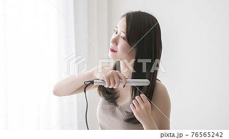 ヘアアイロンで髪の毛をストレートにする若い女性 ヘアアイロンで髪の毛をストレートにする若い女性 76565242