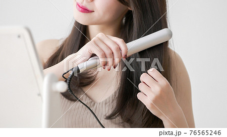 ヘアアイロンで髪の毛をストレートにする若い女性 ヘアアイロンで髪の毛をストレートにする若い女性 76565246