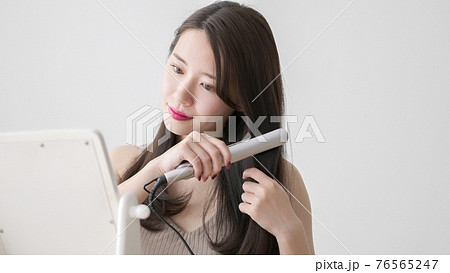 ヘアアイロンで髪の毛をストレートにする若い女性 ヘアアイロンで髪の毛をストレートにする若い女性 76565247