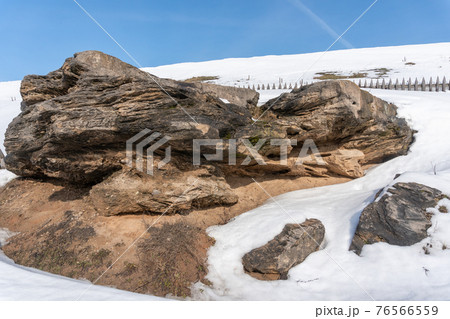 Fenced stone rock in the middle of snowy mountains in winter against a blue sky 76566559