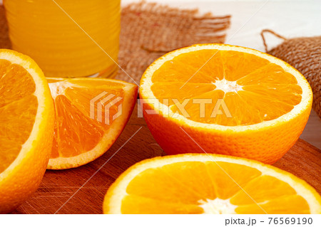 Glass of orange juice and cut oranges on table 76569190