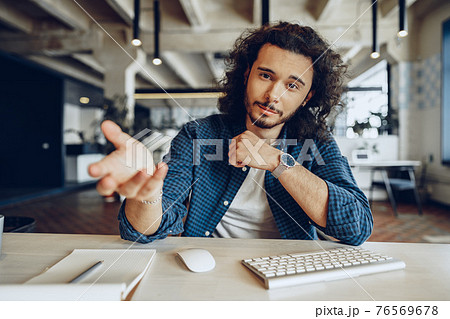 Attractive young handsome businessman sitting in office and talking to you Attractive young handsome businessman sitting in office and talking to you 76569678