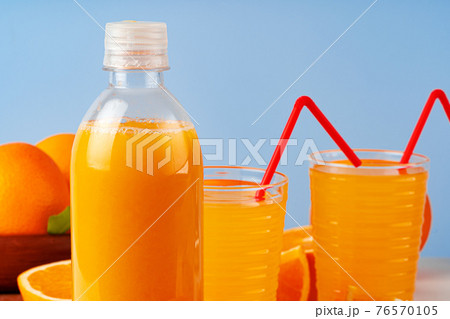 Bottle of orange juice and fresh oranges on table 76570105