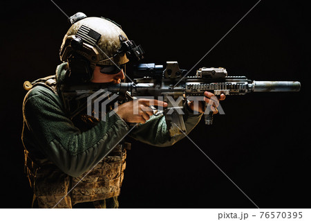 US special forces soldier looking at the aim ready to shoot against black dark background US special forces soldier looking at the aim ready to shoot against black dark background 76570395