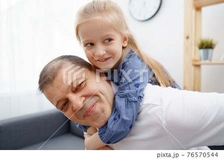 Grandpa and little granddaughter sitting on sofa at home 76570544