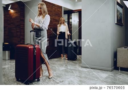 Two young women in formal clothes entering hotel lobby Two young women in formal clothes entering hotel lobby 76570603