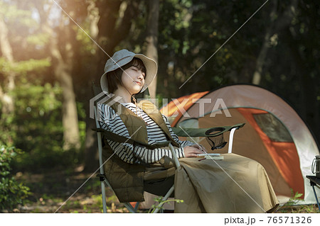 ソロキャンプイメージ テントの前で昼寝する若い女性の写真素材