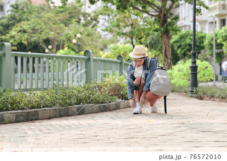 Asian woman with photo camera and backpack in the city Asian woman with photo camera and backpack in the city 76572010
