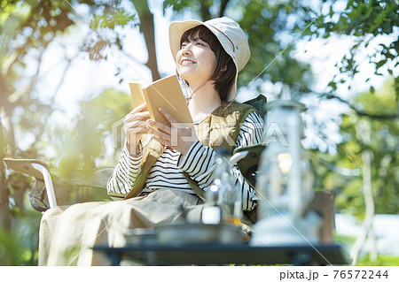 ソロキャンプイメージ・本を読む若い女性 76572244
