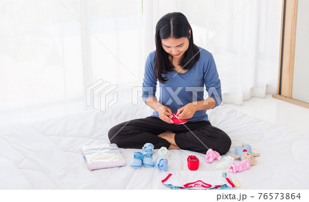 mother preparing baby clothes resting and relaxing on the bed mother preparing baby clothes resting and relaxing on the bed 76573864