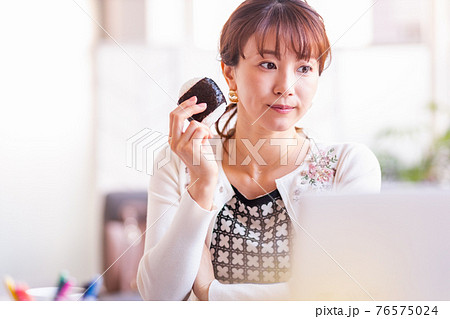明るい室内でおにぎりを食べる女性 明るい室内でおにぎりを食べる女性 76575024