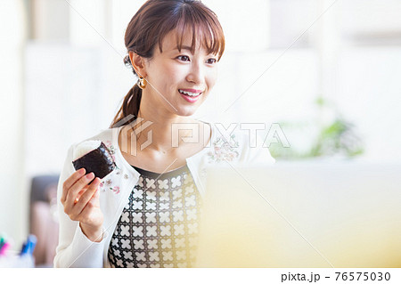 明るい室内でおにぎりを食べる女性 明るい室内でおにぎりを食べる女性 76575030