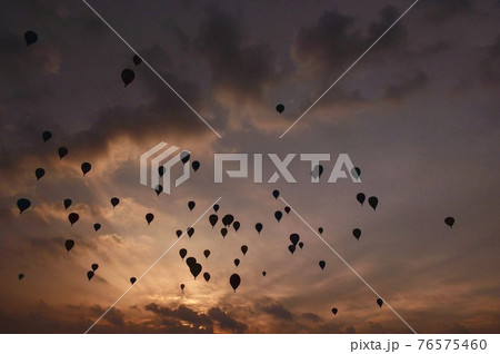 夕焼けの空に舞うバルーン 76575460
