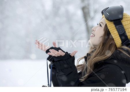 スキー場で降る雪を眺めるスノボ女子 76577194