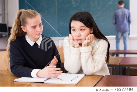 Tired female students during writing notes in classroom Tired female students during writing notes in classroom 76577494