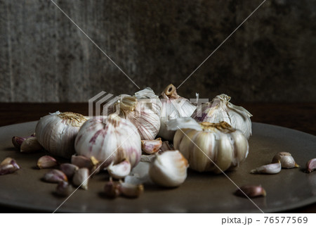 Garlic bulbs and Garlic cloves in Ceramic plate on Wooden rustic table. 76577569