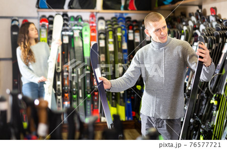 Positive guy and girl are choosing skis Positive guy and girl are choosing skis 76577721