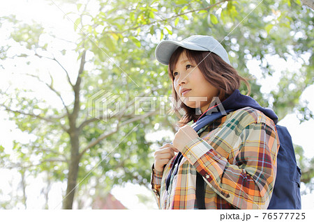 木漏れ日と登山道を登っていく一人の女性 76577725