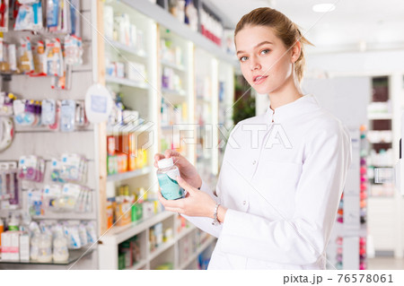 Young friendly pharmacist offering reliable medicine in pharmacy Young friendly pharmacist offering reliable medicine in pharmacy 76578061