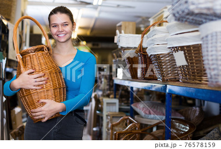Young female holding wicker barrel in decorstore Young female holding wicker barrel in decorstore 76578159