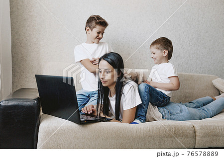 noisy children distract mothers from working at the computer. annoyed mom holds her head noisy children distract mothers from working at the computer. annoyed mom holds her head 76578889