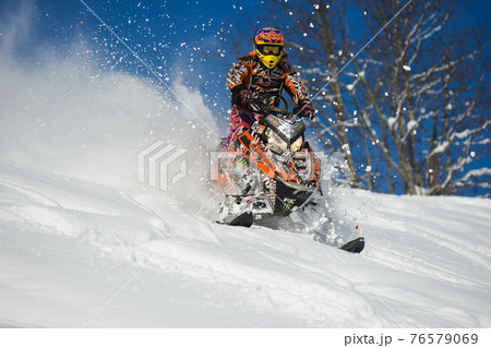 Athlete on a snowmobile moving in the mountains 76579069