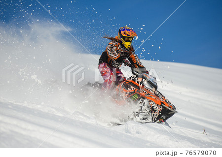 Athlete on a snowmobile moving in the mountains 76579070