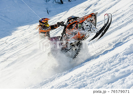 Athlete on a snowmobile moving in the mountains 76579071