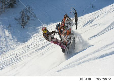 Athlete on a snowmobile moving in the mountains 76579072