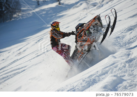 Athlete on a snowmobile moving in the mountains 76579073