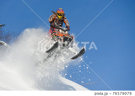 Athlete on a snowmobile moving in the mountains 76579079