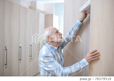 Gray-haired mature man in a changing room in spa center 76579519