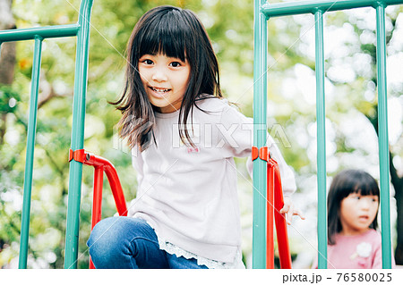 公園で楽しく遊ぶ2人の女の子たち 76580025