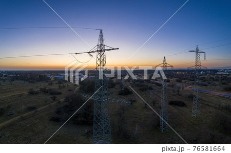 Panoramic image of power pylons against spectacular sunset red at dusk with cloudless sky Panoramic image of power pylons against spectacular sunset red at dusk with cloudless sky 76581664